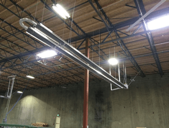 Long industrial tubes suspended from the ceiling of a warehouse, highlighting a structured setup for airflow or lighting in an expansive space.